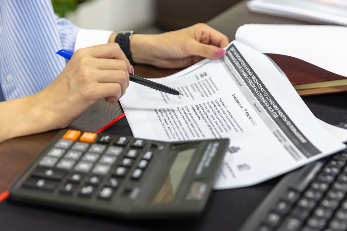 Person reviewing documents with a calculator and pen