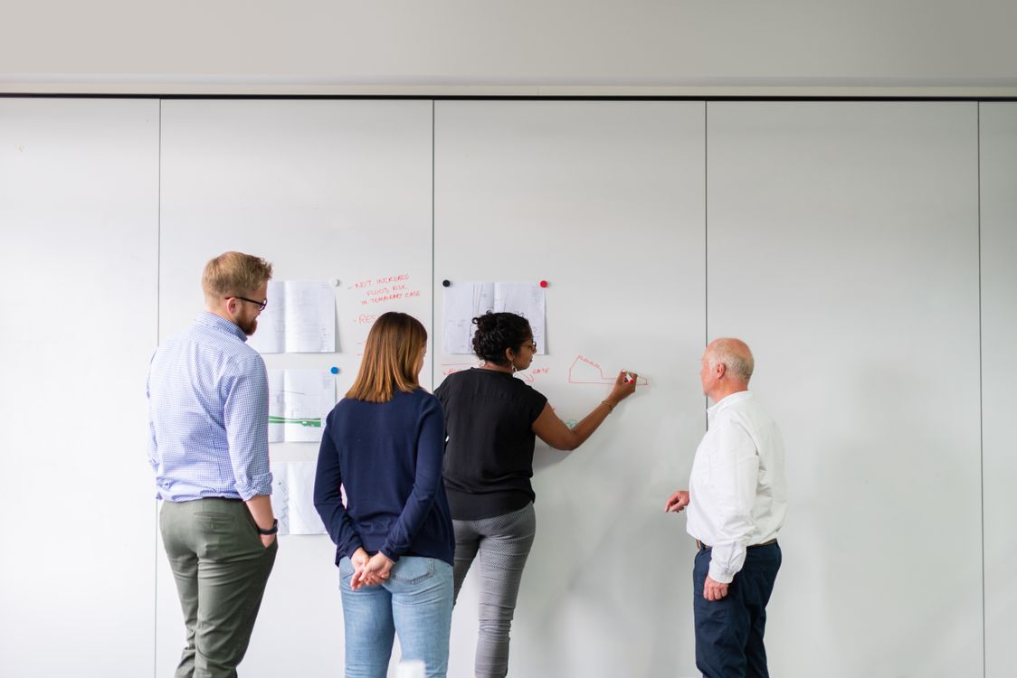 Team discussing a plan together at a whiteboard